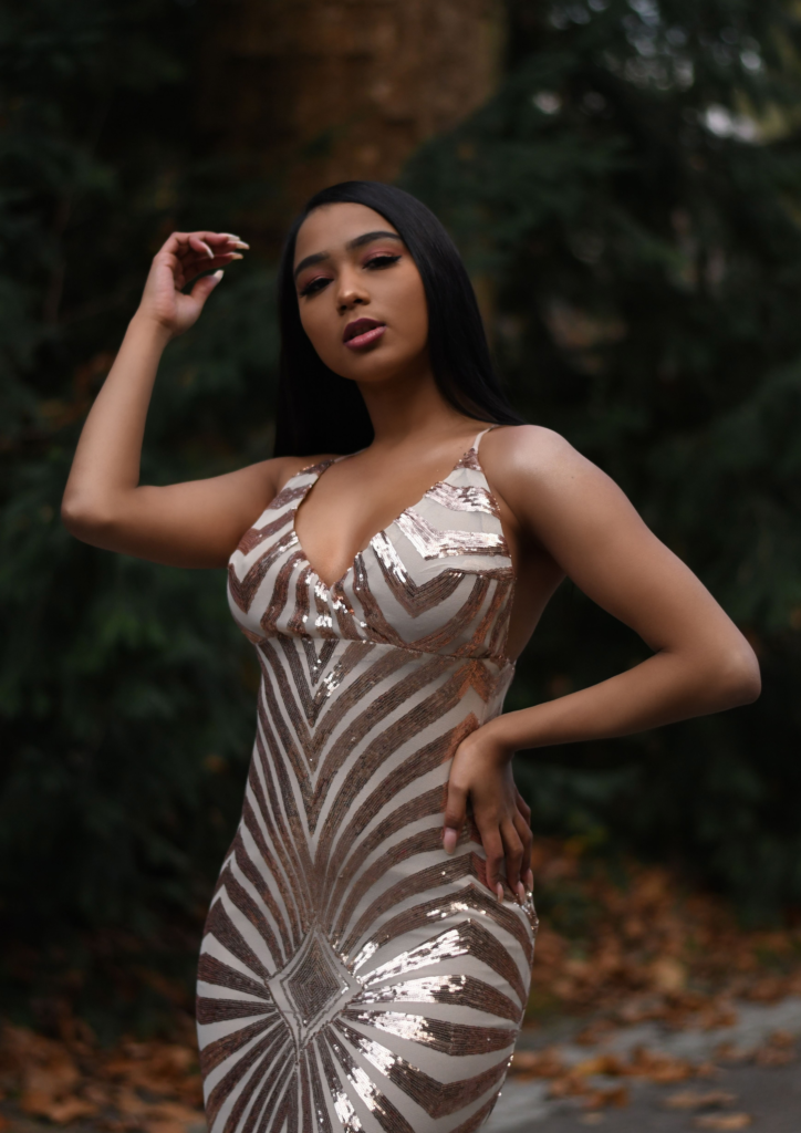 Woman posing in a shimmering dress outdoors.