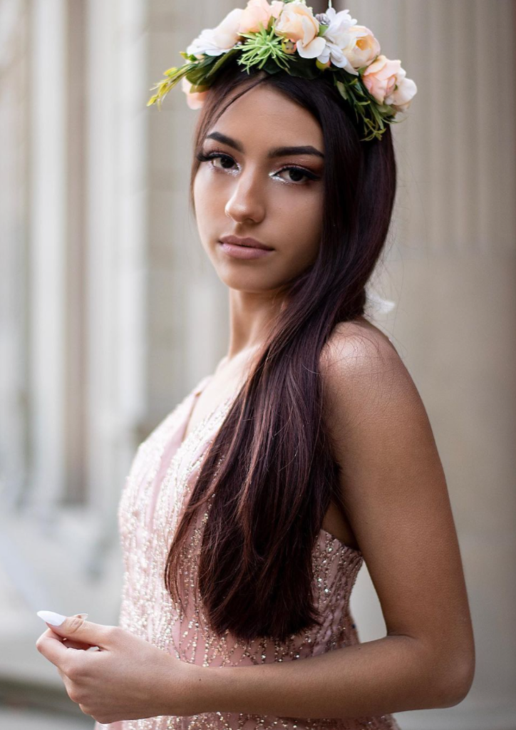 Woman wearing a flower crown, looking at the camera in an elegant setting.
