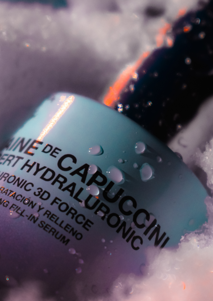 A bottle of skincare serum partially covered in foam with lighting reflections.