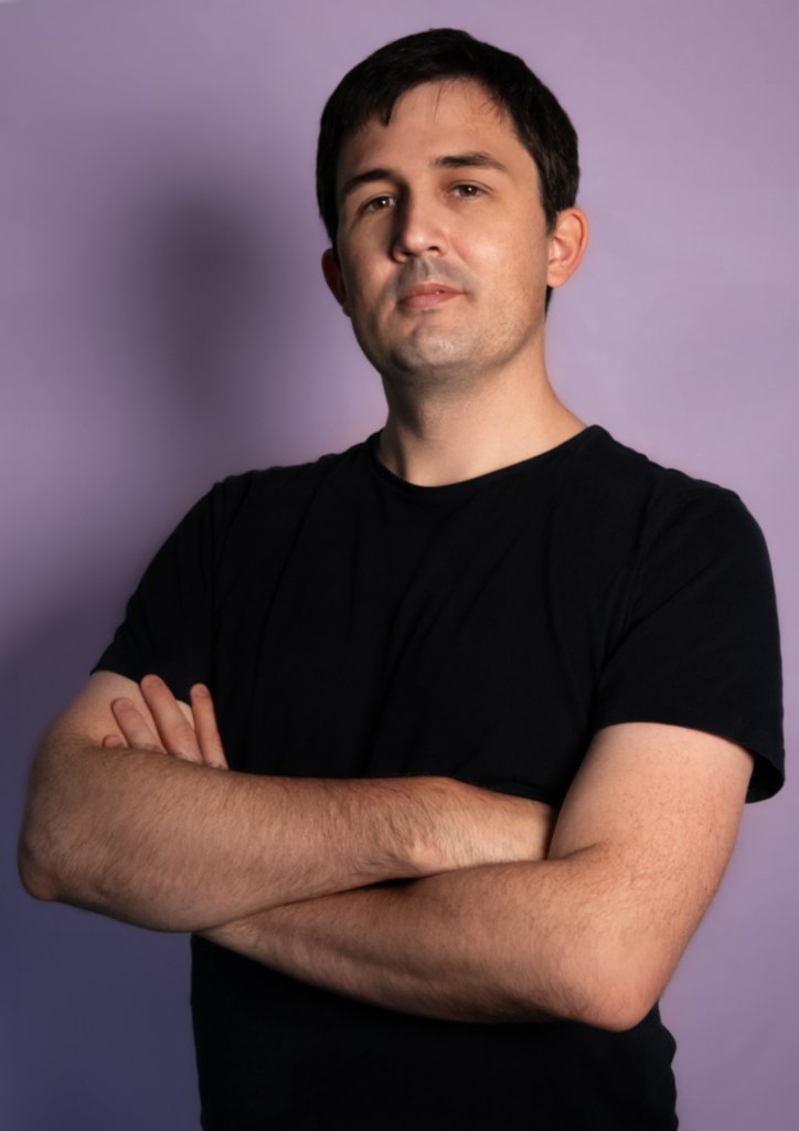 Man with arms crossed against a purple background